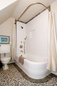 a white bath tub sitting under a window next to a toilet in a bathroom with tiled floors