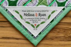 a green and white wedding handkerchief on top of a wooden table