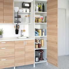 a kitchen with wooden cabinets and white counter tops, including an open door to the pantry