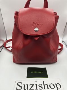 A cherry red leather mini backpack designed by Longchamp for those who have an on-the-go lifestyle. Longchamp Leather mini Backpack color: cherry leather exterior, textile lining single top handle with dual adjustable shoulder straps foldover flap with snap closure drawstring closure under flap interior features zip wall pocketMeasures 10" (H) x 8.25" (W) x 3.5" (D) All products sold on suzishop are guaranteed to be authentic. Sale items are purchased directly from authorized dealers or respecte Longchamp Le Pliage Brown, Longchamp Le Pliage Mini Pouch, Longchamp Small Backpack, Longchamp Backpack, Longchamp Leather, Longchamp Le Pilage Backpack, Cherry Color, Pet Home, Mini Backpack