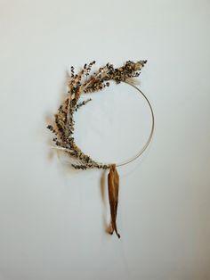 dried flowers are arranged in a circle on a white surface with a wooden stick attached to it