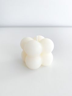 three white balls sitting on top of each other in front of a white wall and floor