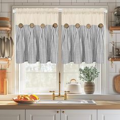 a kitchen window with two tiered valances hanging from the side and fruit on the counter