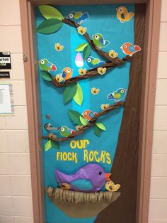 a door decorated with paper birds and tree branches, which reads our flock roosts