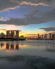 the sun is setting over singapore's skyline as seen from across the water with boats in the foreground