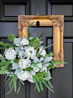 a wreath with white flowers and greenery hangs on the front door