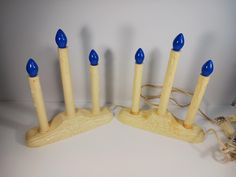 four wooden candles with blue tops are sitting on a white surface next to a cord