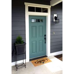 a blue front door on a gray house with a black chair and potted plant