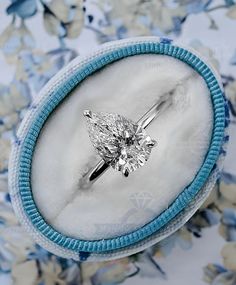 a ring with a diamond in it sitting on top of a blue and white flowered background