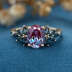 a red and blue ring sitting on top of a blue surface with flowers in the background