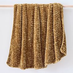 a brown blanket hanging on a clothes line next to a white wall with a wooden hanger