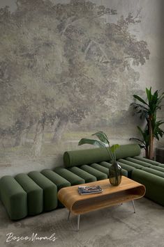 a green couch sitting next to a wooden table in front of a large painting on the wall