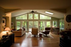 a living room filled with furniture and a ceiling fan in the middle of an open floor plan