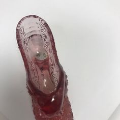 a red glass shoe sitting on top of a white table