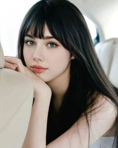 a woman with long black hair and blue eyes posing for a photo in a car