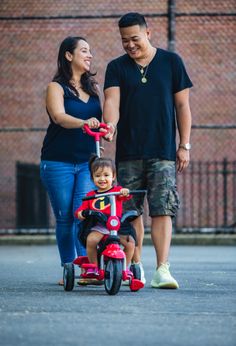 a man, woman and child are walking on the street with their tricycles