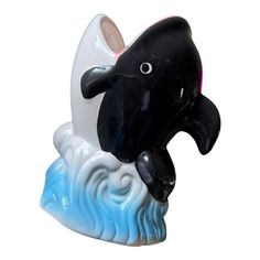 a black and white dolphin figurine sitting on top of a wave