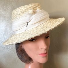 This Beautiful 1950s' Cream Colored Straw Hat Consists Of A Medium Height Crown Surrounded By A Medium Brim. The Weaving Of The Straw Is Beautiful And Is Softer Than Other Hats Of The Era. There Is A Draped Matching Color Fabric Band Around The Crown, And A Thick Hairpin With A Little Ball Head Made Of The Same Straw Is Inserted At One Side Of The Front. There Is A Small Bow At The Back. Lebel: There Is An Illegible Printed Label On The Inside Hatband, Which Most Likely Is A Consumer Protection Label. This Is An Authentic Piece Of Fashion History! This Hat Is In Wonderful Vintage Condition & Has Been Lovingly Preserved Among Over 1300 Vintage Hats We Have Collected For 40+ Years. Feathers Fitted Retro Cream Hat, Retro Fitted Cream Hat, Retro Cream Hat, Vintage Cream Hat For Vintage Events, Cream Vintage Hat For Vintage Events, White Fitted Retro Hat, Vintage Fitted Straw Hat For Formal Occasions, Classic Straw Hat For Spring Wedding, Retro Fitted Hats For Spring