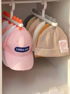 hats and caps are hanging on hooks in a closet with labels that say i miss you