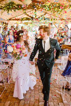 a bride and groom walk down the aisle as confetti falls around them