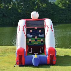 an inflatable baseball game is set up on the grass near a body of water