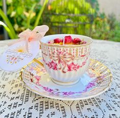 a teacup filled with roses sitting on top of a table next to a tag