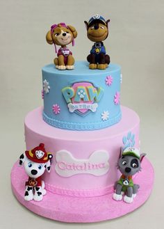 there are three dogs on the top of this pink and blue tiered birthday cake