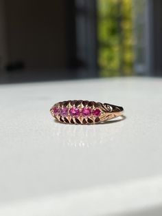 An antique ruby boat style ring, set on 9ct gold with decorative shoulders and setting.   The ring has lovely clear hallmarks for Birmingham and dated to 1912 - making it 112 years old. In very good condition.  The ring has a 5 pink-ish red ruby stones in a 'boat ring' style setting and with decorative shoulders.   Current size R. Approximate weight is 2.8g. Please note we would recommend that this ring is not significantly resized, to avoid damage to the hallmarks and overall shape and design o Pink Hallmarked Victorian Ruby Ring, Victorian Pink Hallmarked Ruby Ring, Pink Victorian Hallmarked Ruby Ring, Antique Pink Ruby Ring, Vintage Red Sapphire Ring, Antique Pink Ruby Ring With Rose Cut Diamonds, Antique Hallmarked Ruby Ring, Victorian Style Ruby Ring Stamped 14k, Antique 14k Stamped Ruby Ring