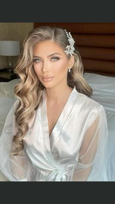 a woman sitting on top of a bed wearing a white dress