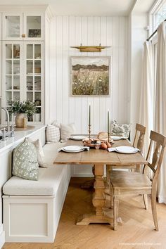 a kitchen with white walls and wooden floors, along with a table set for four