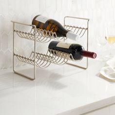 two bottles of wine are sitting in a metal rack on a countertop next to some glasses