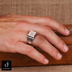 a man's hand with a ring on top of a wooden box that is sitting on a couch