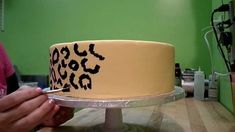 a person is decorating a cake with black letters