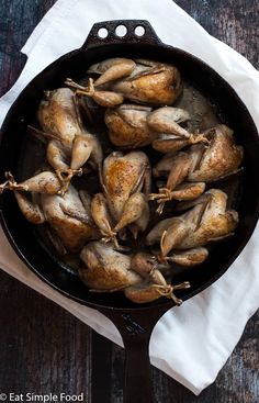 chicken in a cast iron skillet on top of a white napkin next to a wooden table