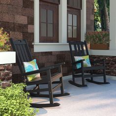 two black rocking chairs sitting on top of a porch