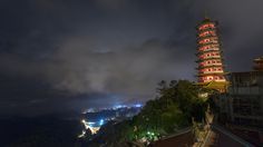 a tall tower lit up at night on top of a hill