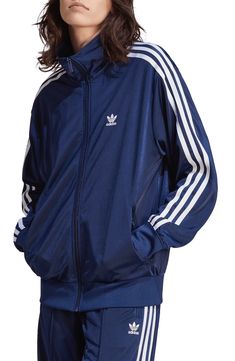 The brand's iconic 3-Stripes make an appearance tracing the shoulders and sleeves of a sporty track jacket crafted with a loose fit for more room to move. Front zip closure Stand collar Front zip pockets 100% recycled polyester Machine wash, tumble dry Imported Quoi Porter, Adidas Tracksuit, Shiny Fabric, Adidas Trefoil, Adidas Shop, Women Lifestyle, Firebird, Blue Adidas, Adidas Online