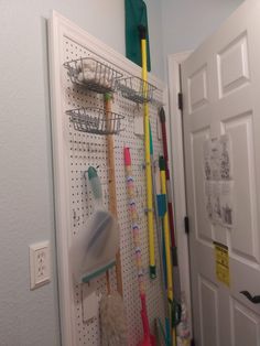 a white pegboard with lots of cleaning supplies hanging on it's side next to a door