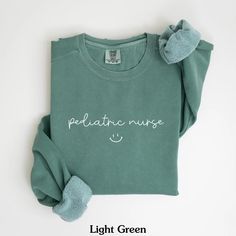 a green shirt with the words pediatric nurse on it and a pair of mitts next to it