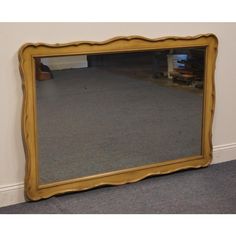 a large gold framed mirror sitting on top of a carpeted floor next to a wall