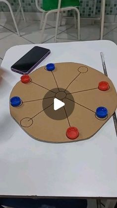 a cell phone sitting on top of a table next to a game board with red, white and blue buttons