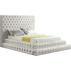 a white bed with tufted headboard and foot board, made in an upholstered style