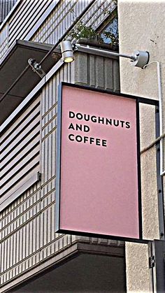 a pink sign hanging from the side of a tall building next to a street light