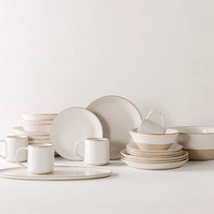 a table topped with lots of white plates and cups