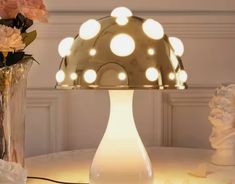 a table topped with a vase filled with flowers next to a lighted mushroom shaped lamp