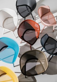 four different colored chairs sitting next to each other on top of a white flooring