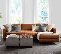 a living room filled with lots of furniture next to two large windows and a coffee table