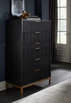 a black dresser with gold handles in a room