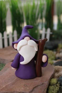 a purple gnome figurine holding a piece of wood on top of a rock