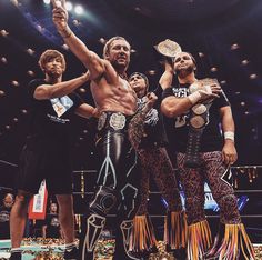 a group of men standing on top of a stage with their arms in the air